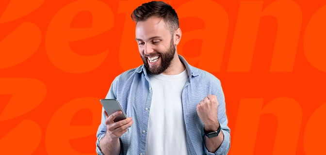 Imagem mostra homem sorrindo ao utilizar um smartphone