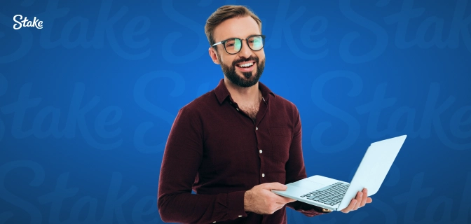 imagem mostra homem sorrindo enquanto segura um notebook