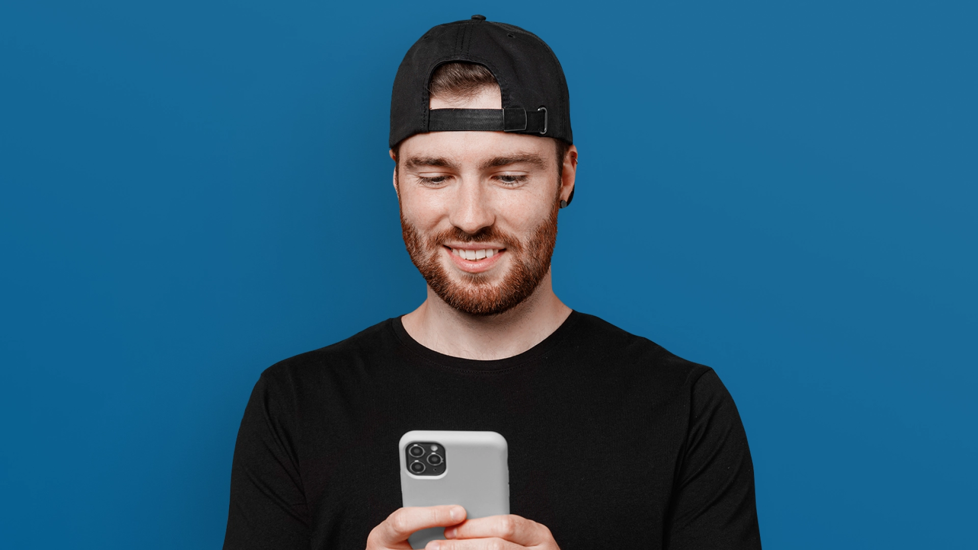 Imagem mostra homem sorrindo ao utilizar um celular