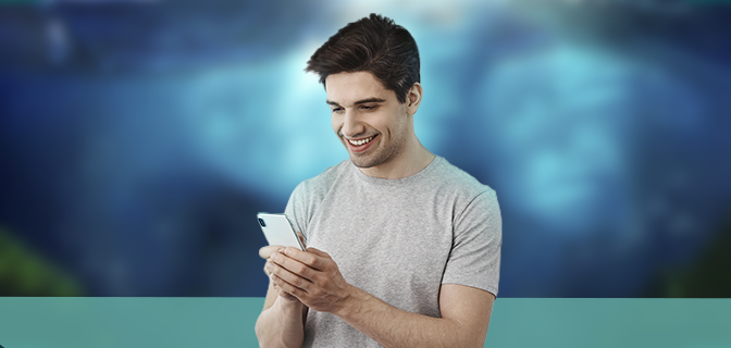 Imagem mostra homem sorrindo enquanto segura smartphone